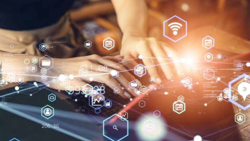 Personne utilisant un ordinateur portable avec des icônes numériques flottantes représentant la connectivité et les technologies de linformation