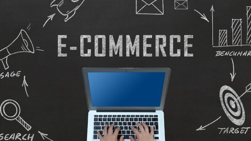 Personne utilisant un ordinateur portable avec un schéma de stratégie e commerce dessiné sur un tableau noir