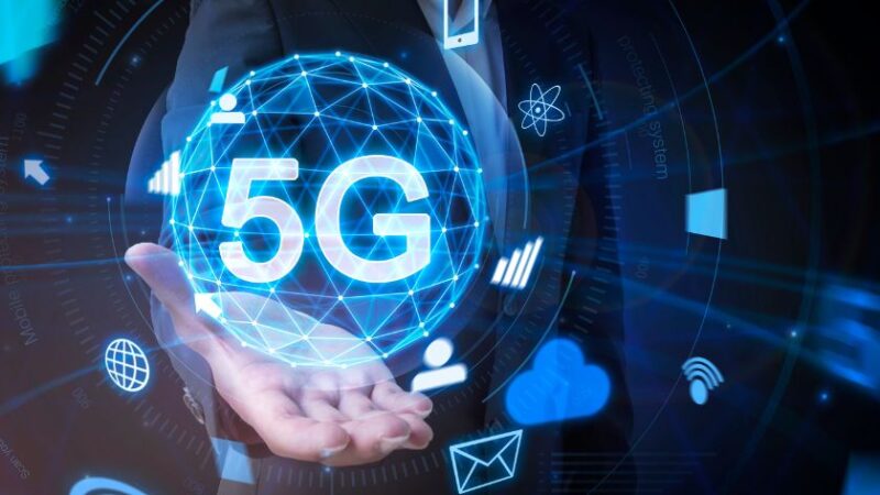 Homme daffaires tenant un hologramme lumineux représentant la technologie 5G entourée dicônes de connectivité et de communication