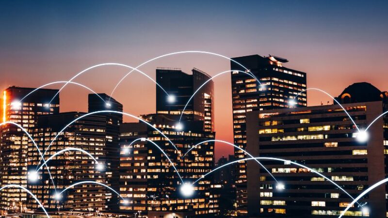 Connexions lumineuses reliant des bâtiments dans une ville intelligente au coucher du soleil