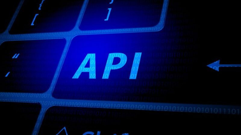 Gros plan sur une touche de clavier dordinateur avec linscription API en bleu lumineux entourée de symboles de code