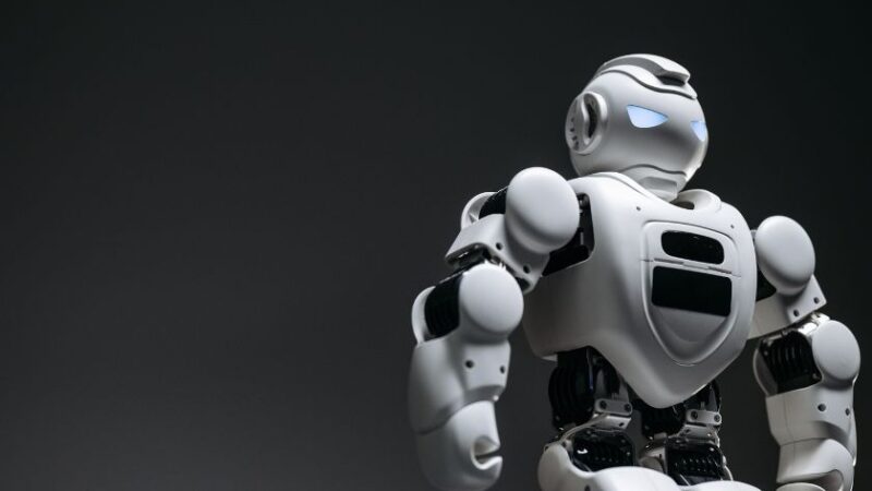 Petit robot humanoïde moderne avec articulations mécaniques sur fond sombre