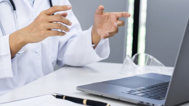 Médecin en blouse blanche utilisant un ordinateur portable pour une téléconsultation médicale