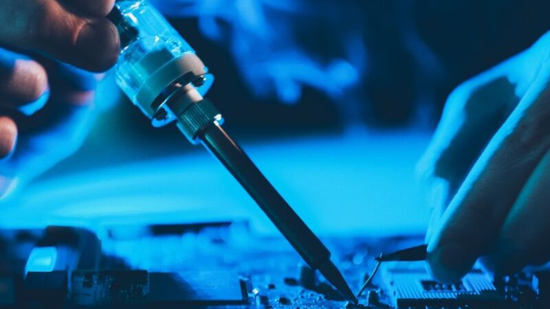 Technicien utilisant un fer à souder pour réparer une carte électronique dordinateur