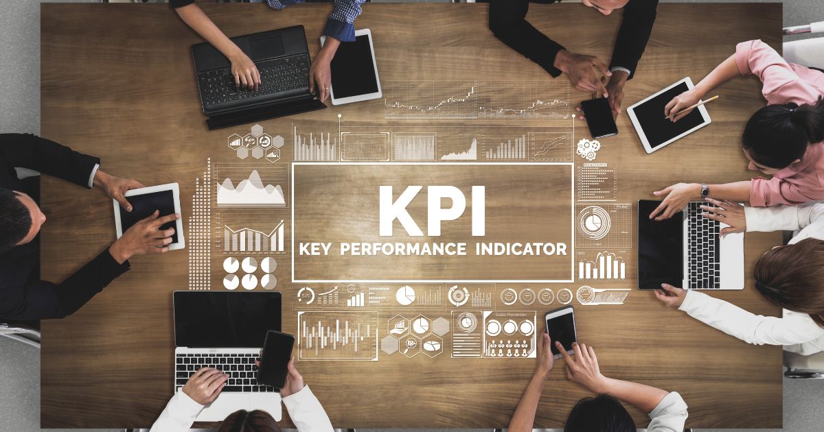 Réunion déquipe autour dune table avec ordinateurs et tablettes KPI affichés en surimpression
