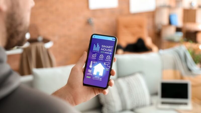 Personne utilisant un smartphone pour contrôler une maison intelligente via une application IoT