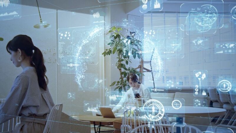 Femmes travaillant dans un bureau moderne avec des hologrammes de données illustrant lintégration de lIA dans les systèmes ERP