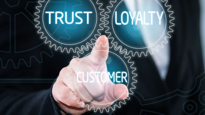 Main dun homme daffaires pointant trois engrenages virtuels étiquetés Trust Loyalty et Customer