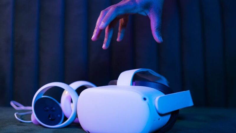 Main tendue vers un casque de réalité virtuelle avec manettes symbolisant ladoption de la VR et AR dans les entreprises