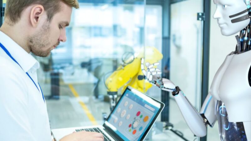 Ingénieur travaillant sur un ordinateur portable en interaction avec un robot humanoïde