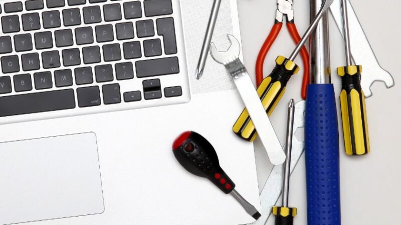 Clavier dordinateur portable entouré doutils de réparation tournevis marteau pinces illustrant la maintenance informatique et lintervention technique