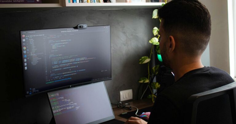 Développeur travaillant sur deux écrans affichant du code informatique dans un bureau moderne