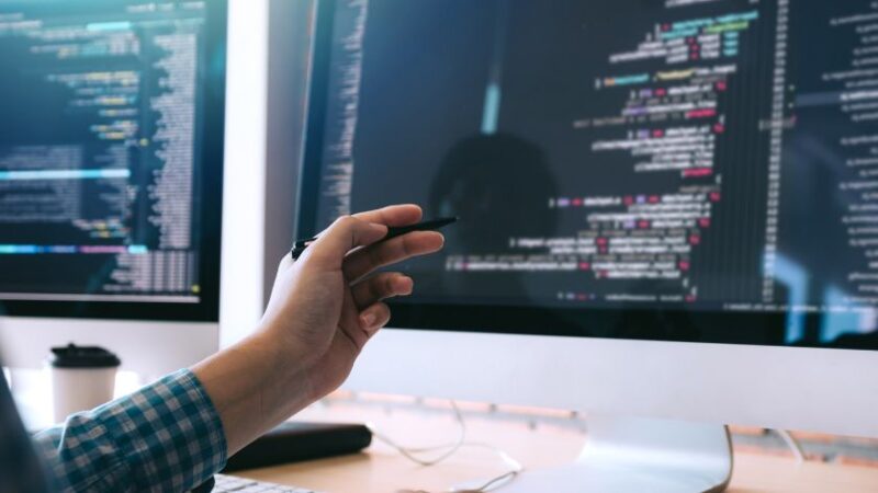 Développeur travaillant sur un programme informatique affiché sur deux écrans