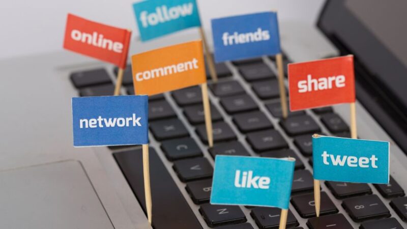Clavier dordinateur avec des drapeaux colorés affichant des mots liés aux réseaux sociaux comme like share tweet comment follow