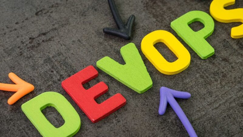 Mot DEVOPS en lettres colorées avec des flèches multicolores sur fond sombre représentant la collaboration et lintégration continue