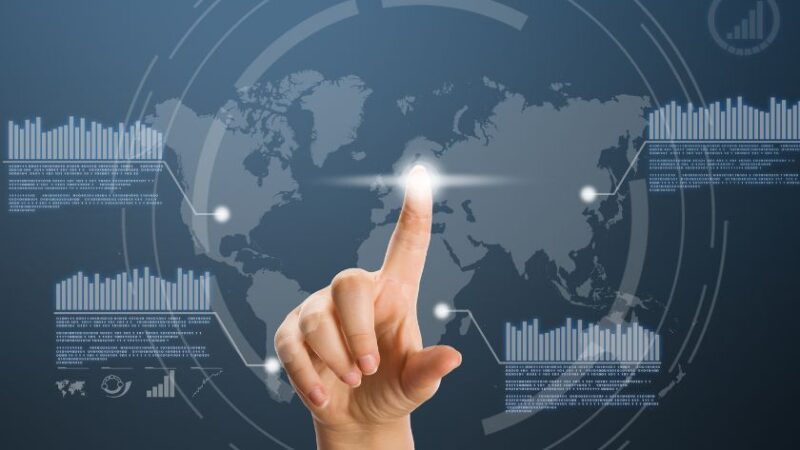 Main touchant une carte du monde numérique avec des graphiques interactifs symbolisant la transformation digitale et lanalyse des données globales