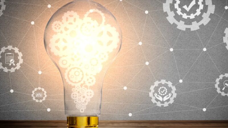 Ampoule allumée avec engrenages lumineux à lintérieur symbolisant linnovation loptimisation des processus et lintelligence opérationnelle