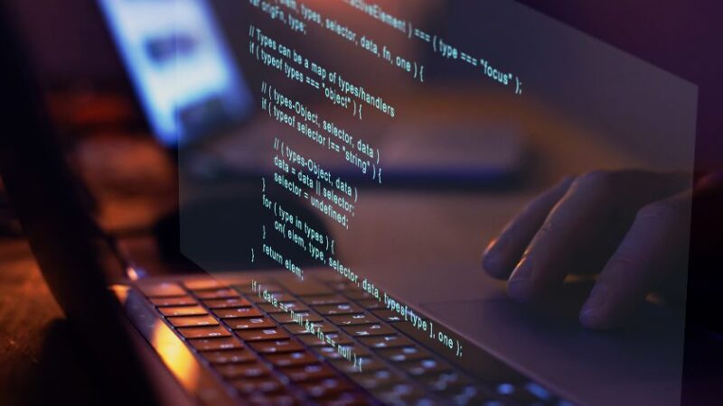 Développeur tapant du code sur un ordinateur portable avec affichage de lignes de code en surimpression
