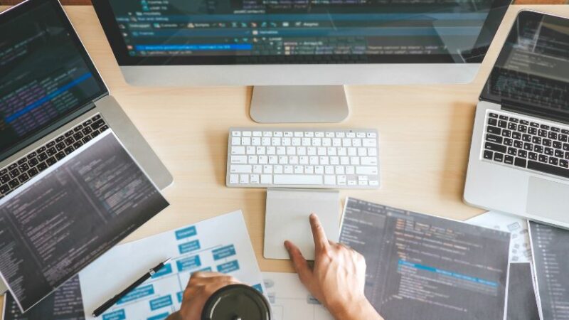 Poste de travail dun développeur avec plusieurs écrans affichant du code et des schémas techniques