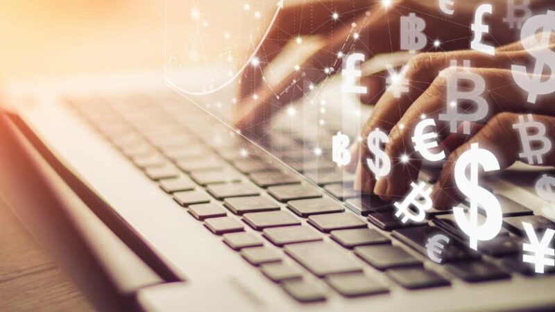 Mains tapant sur un clavier dordinateur portable avec des symboles monétaires numériques flottants