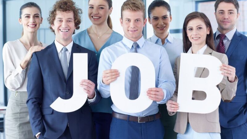 Groupe de jeunes professionnels souriants tenant les lettres formant le mot JOB dans un bureau moderne