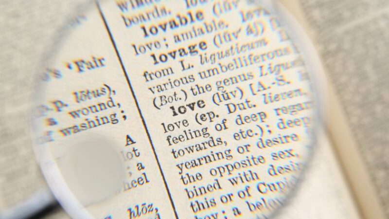 Loupe grossissant le mot love dans un dictionnaire imprimé