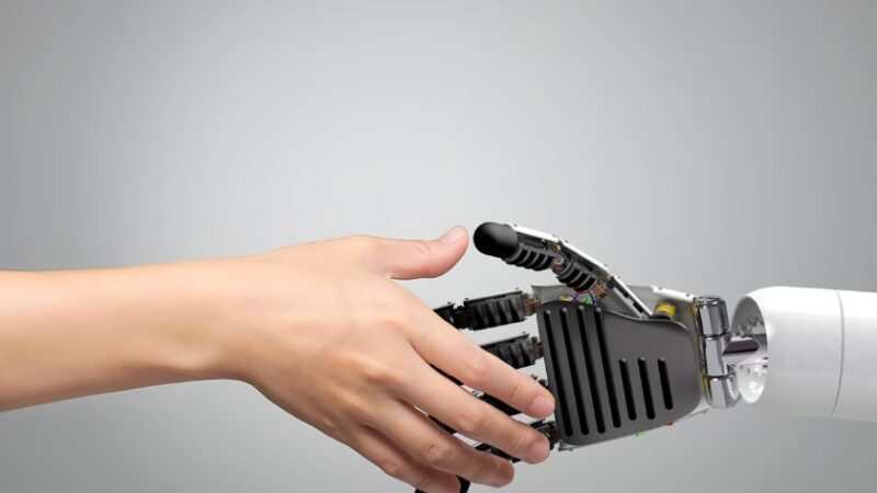 Main humaine serrant une main robotique symbolisant la collaboration entre lhomme et lintelligence artificielle