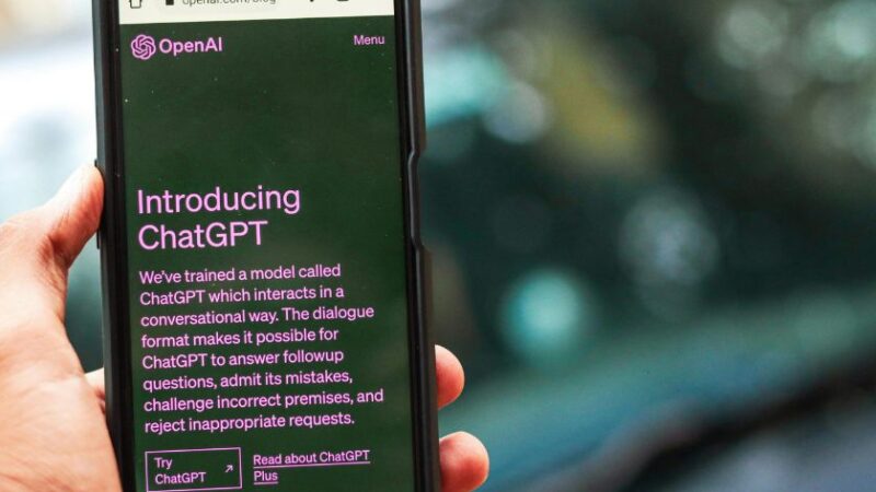 Main tenant un smartphone affichant la page dintroduction de ChatGPT sur le site dOpenAI